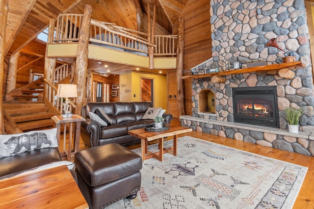 living room with wooden walls, wood finished floors, wooden ceiling, a fireplace, and high vaulted ceiling