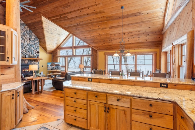 kitchen with wood ceiling, light stone countertops, hanging light fixtures, and a healthy amount of sunlight