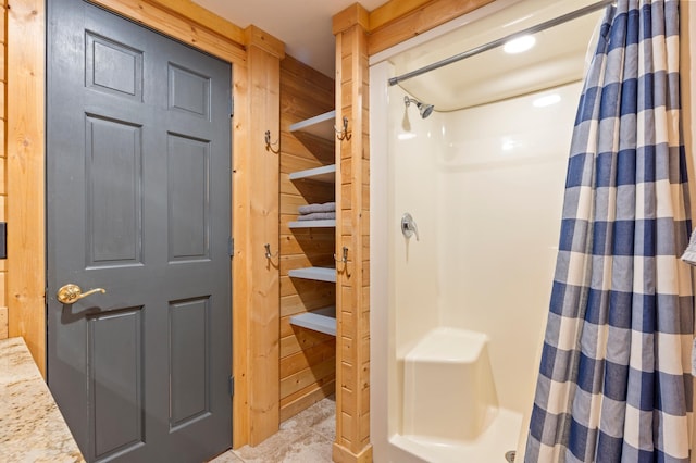 bathroom featuring wood walls and a stall shower