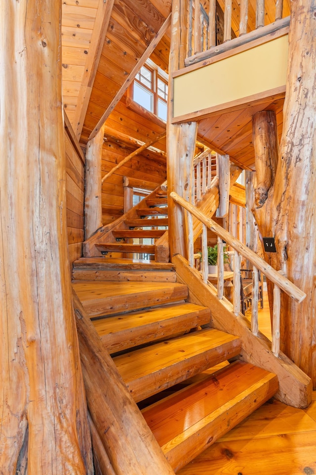 stairs featuring wooden ceiling, wood finished floors, and a towering ceiling