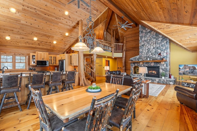 dining area featuring light wood-type flooring, high vaulted ceiling, stairs, wood ceiling, and a fireplace