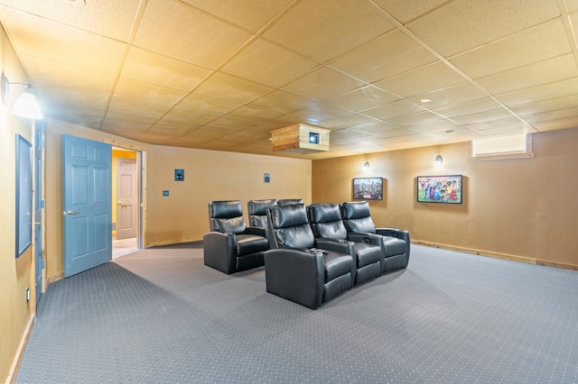 carpeted cinema room featuring a paneled ceiling and baseboards