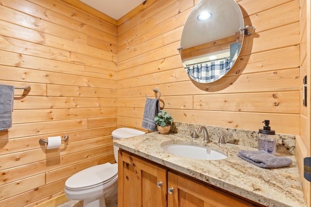 bathroom with wooden walls, toilet, and vanity