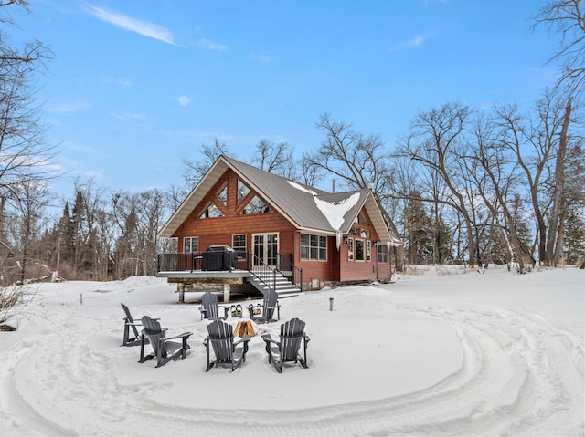 snow covered house with a fire pit and a deck