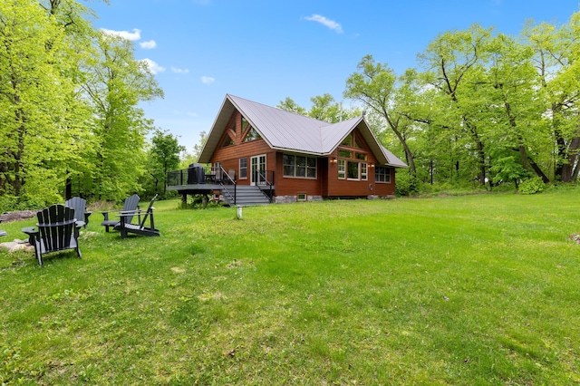 rear view of house featuring a lawn, a deck, and metal roof