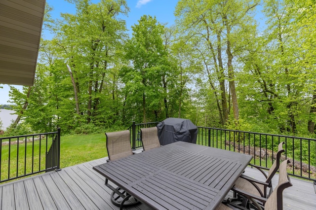 wooden deck featuring outdoor dining space, a lawn, and a grill