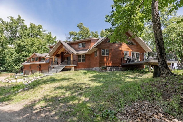 rear view of property with an attached garage, a lawn, a porch, and stairs