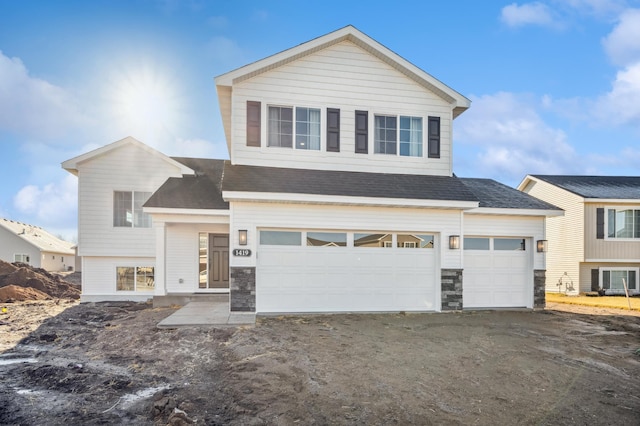 view of front of house featuring driveway, stone siding, an attached garage, and a shingled roof