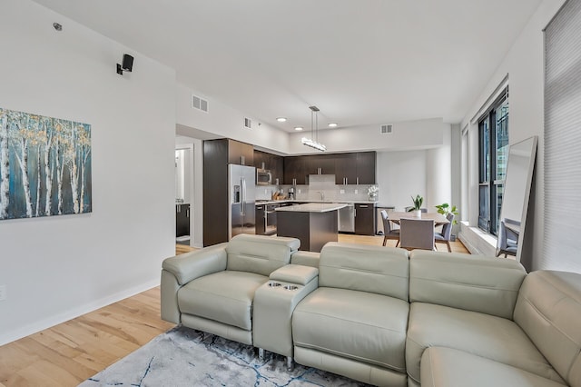 living room featuring light wood-type flooring, visible vents, and baseboards