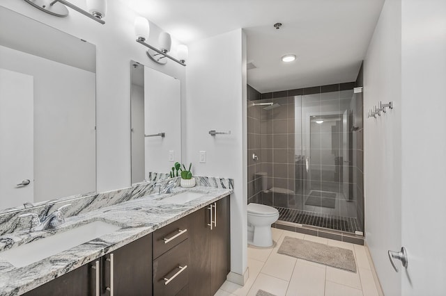 full bathroom featuring double vanity, a stall shower, a sink, and toilet