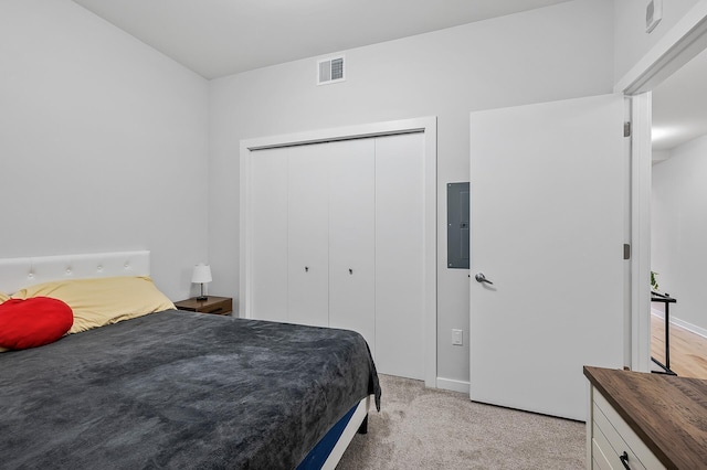 bedroom with a closet, light colored carpet, visible vents, electric panel, and baseboards