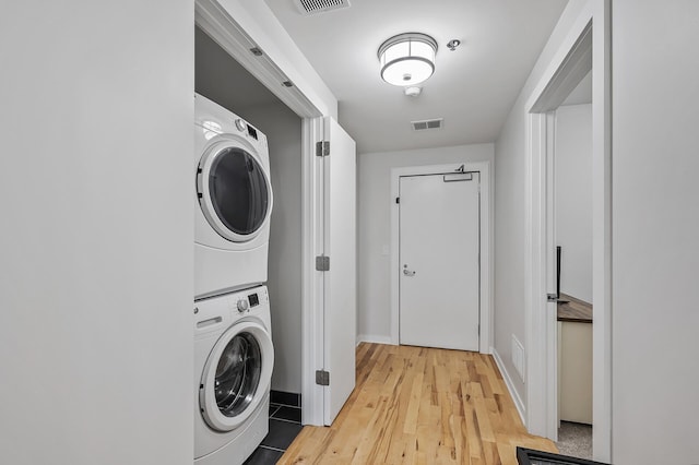 laundry room featuring light wood-style floors, stacked washer and clothes dryer, visible vents, and laundry area