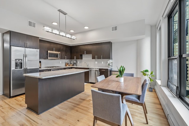 kitchen with a kitchen island, visible vents, dark brown cabinets, appliances with stainless steel finishes, and backsplash