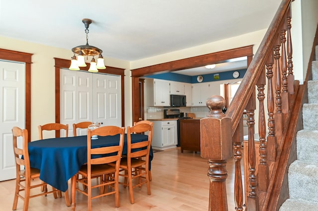 dining area featuring light wood-type flooring, an inviting chandelier, and stairway