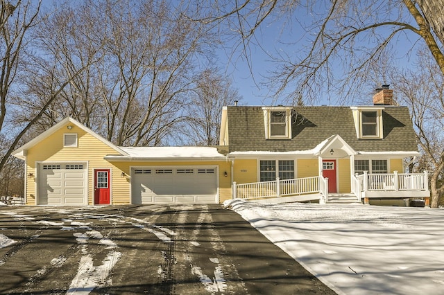 view of front of home featuring a garage, roof with shingles, driveway, and a chimney