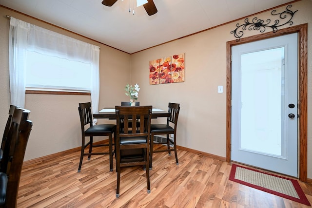 dining room with light wood finished floors, baseboards, a ceiling fan, and crown molding