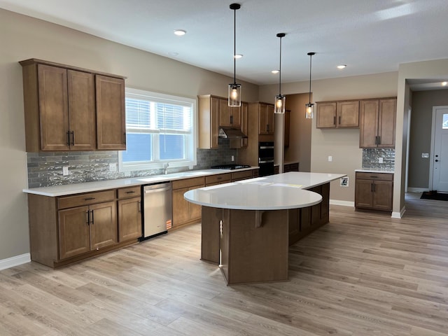 kitchen with brown cabinets, stainless steel appliances, light countertops, and a kitchen island