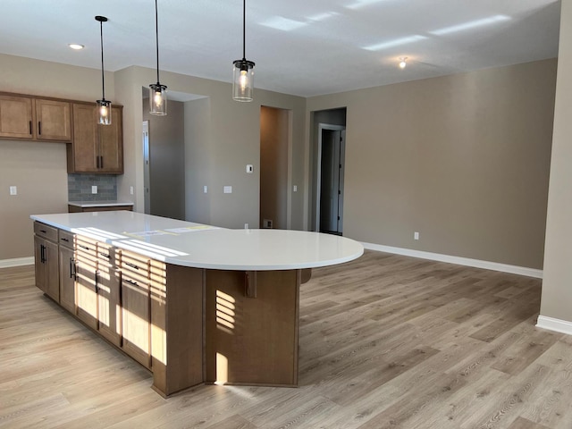 kitchen featuring light wood-style flooring, pendant lighting, light countertops, and a center island