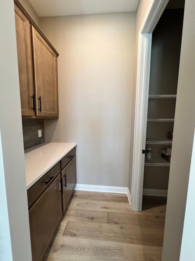 bar featuring light wood finished floors, baseboards, and decorative backsplash