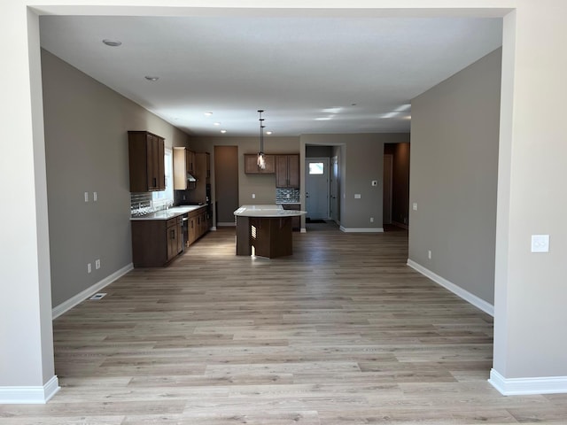 kitchen with baseboards, light countertops, open floor plan, and a center island