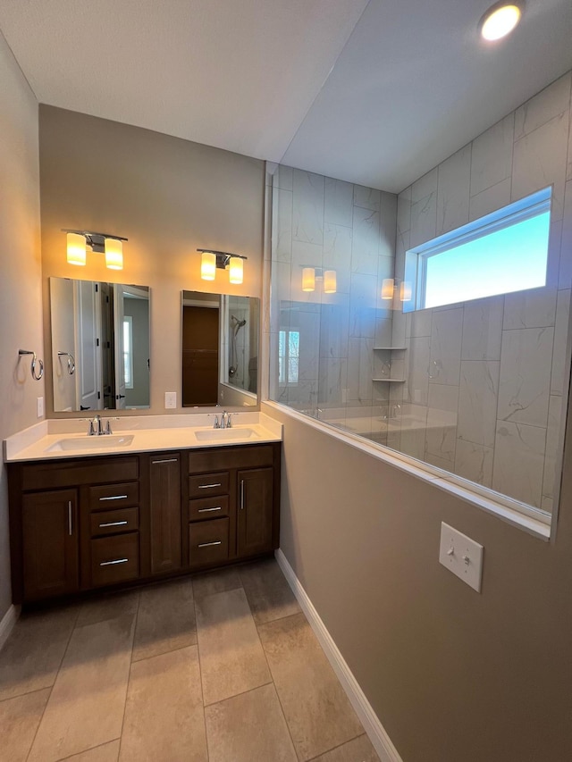 bathroom featuring double vanity, baseboards, a walk in shower, and a sink