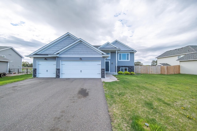 view of front of property with stone siding, driveway, a front lawn, and fence