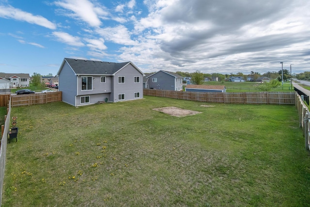 back of property featuring a yard, a fenced backyard, and a residential view