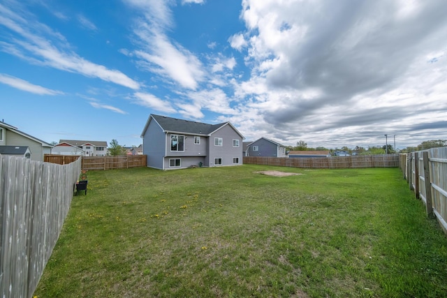 rear view of house featuring a fenced backyard and a lawn