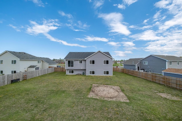 rear view of property featuring a lawn, a fenced backyard, and a residential view