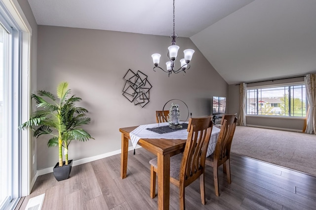 dining room with vaulted ceiling, a notable chandelier, wood finished floors, and baseboards