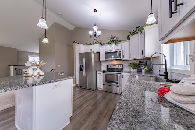 kitchen featuring dark wood finished floors, stainless steel appliances, white cabinetry, pendant lighting, and a sink