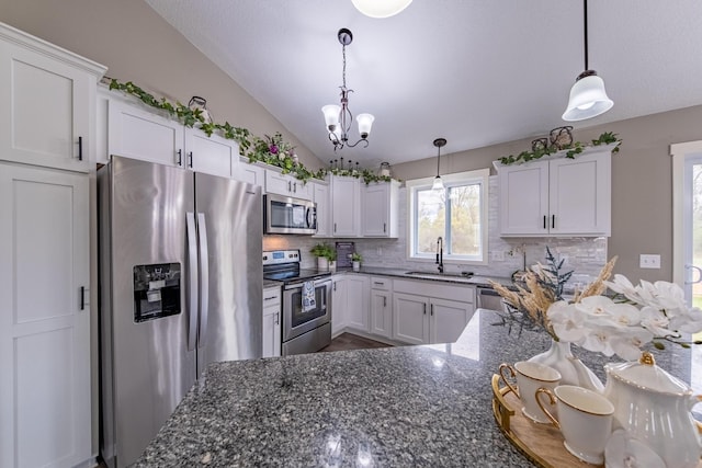 kitchen featuring dark stone counters, hanging light fixtures, appliances with stainless steel finishes, and white cabinetry