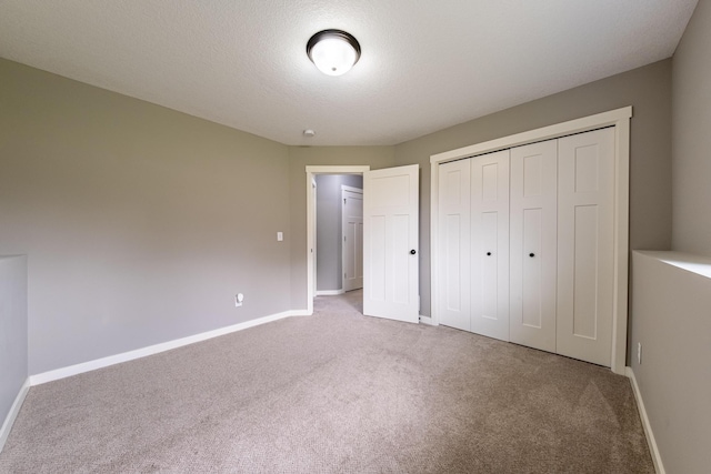 unfurnished bedroom featuring carpet, a closet, a textured ceiling, and baseboards