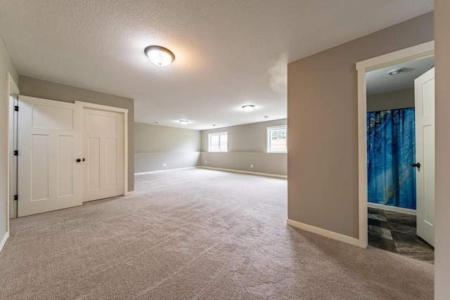 below grade area with carpet flooring, a textured ceiling, and baseboards