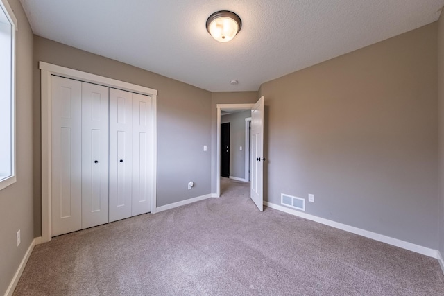 unfurnished bedroom featuring a closet, visible vents, light carpet, and baseboards