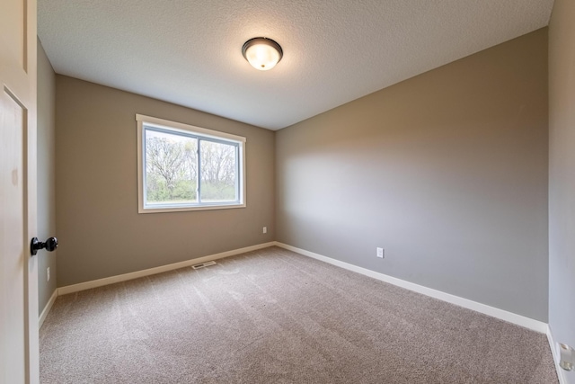 empty room featuring a textured ceiling, carpet floors, visible vents, and baseboards