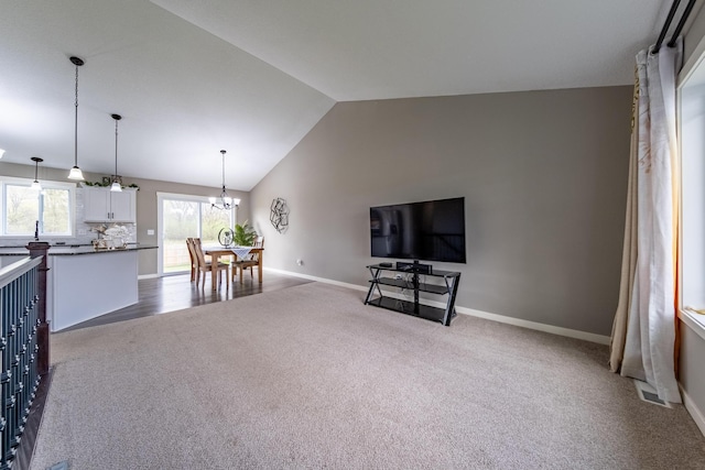 living area featuring carpet floors, a notable chandelier, vaulted ceiling, and baseboards