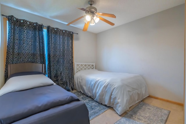 carpeted bedroom featuring baseboards and a ceiling fan