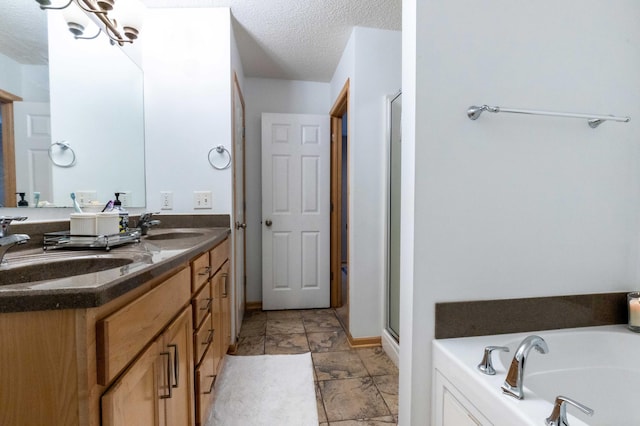 bathroom featuring a textured ceiling, a stall shower, a sink, and a garden tub