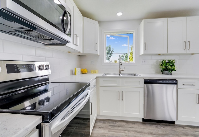 kitchen with light wood-style flooring, white cabinetry, stainless steel appliances, and a sink