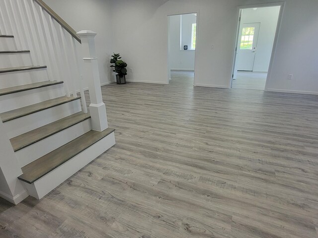 interior space featuring light wood-style floors, stairway, and baseboards