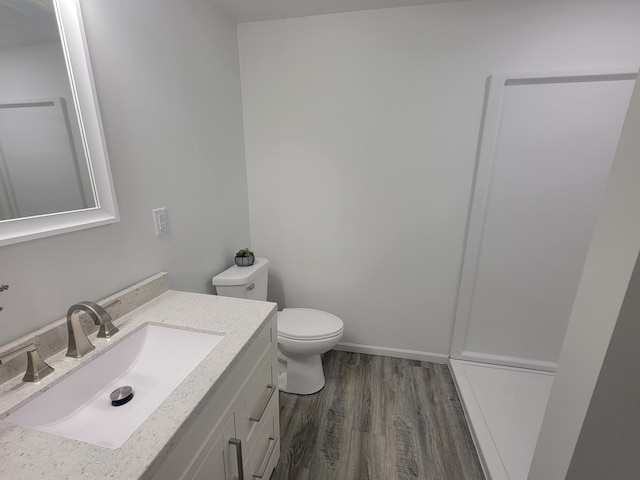 bathroom with toilet, baseboards, wood finished floors, and vanity