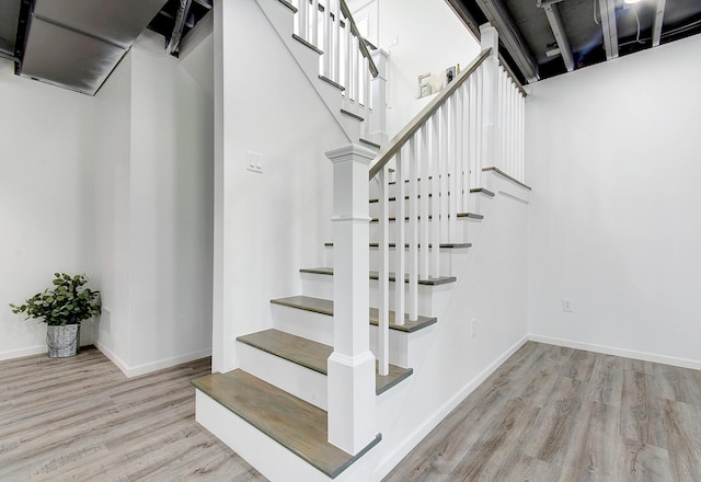 staircase featuring baseboards and wood finished floors