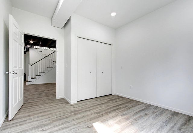 unfurnished bedroom featuring light wood finished floors, a closet, recessed lighting, and baseboards