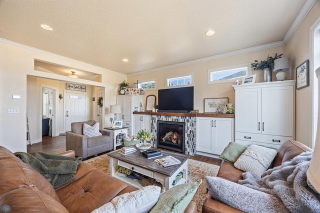 living area featuring a glass covered fireplace, a textured ceiling, wood finished floors, and crown molding