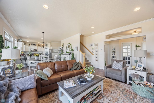 living area with ornamental molding, a textured ceiling, and wood finished floors