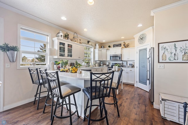 kitchen with a peninsula, a kitchen breakfast bar, ornamental molding, and stainless steel appliances