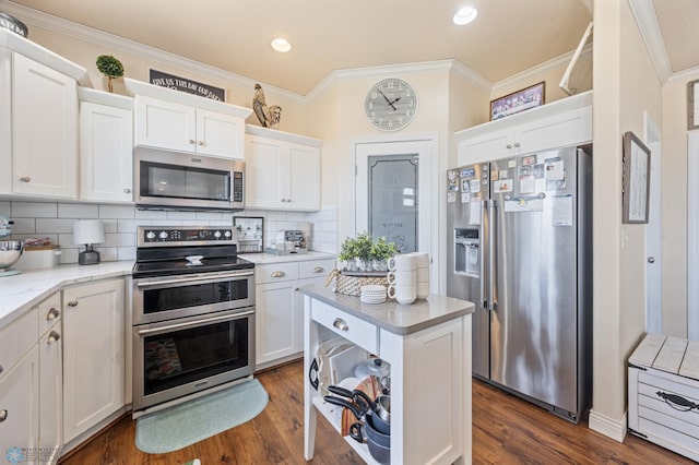 kitchen with dark wood finished floors, ornamental molding, stainless steel appliances, white cabinetry, and tasteful backsplash