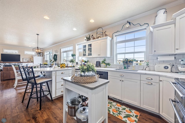 kitchen with dark wood finished floors, white cabinets, ornamental molding, and a center island