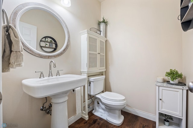 half bath featuring toilet, wood finished floors, and baseboards